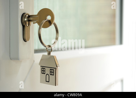 HOUSE KEY IN DOOR LOCK WITH HOUSE KEY FOB RE HOME BUYERS FIRST TIME BUYING HOMES HOUSES HOUSING MARKET MORTGAGES INCOMES UK Stock Photo