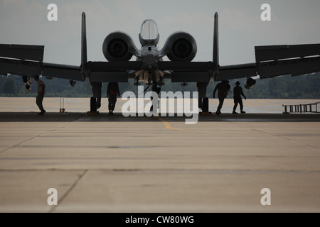 Maintenance airmen from the 127th Maintenance Squadron are seen in silhouette as they work to recover an A-10 Thunderbolt II after a flight at Selfridge Air National Guard Base, Mich., Aug. 10, 2012. This aircraft is operated by the 107th Fighter Squadron, Michigan Air National Guard. Stock Photo