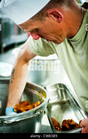 PARWAN PROVINCE, Afghanistan - Spc. Jeremy Newton, a Task Force Atlas, 82nd Combat Aviation Brigade food service specialist from Sierra Vista, Ariz., scoops buffalo wings out of a pot and in to a serving tray. The wings were served up next to steak, crab legs, ribs and burgers as the aviation dining facility emptied its coolers and cupboards on their final day of business. The popular facility, which often saw 30-minute lines on Friday night closed its doors permanently on Aug. 17. Stock Photo