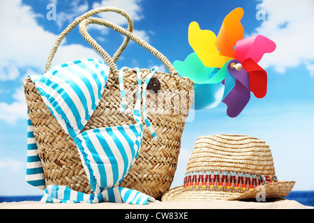 Closeup of summer beach bag with items on sandy beach Stock Photo