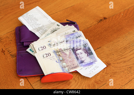 sterling notes, a shopping receipt and an open purse on a wooden table ...