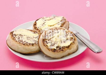 Buttered English crumpets served on a white china tea plate Stock Photo