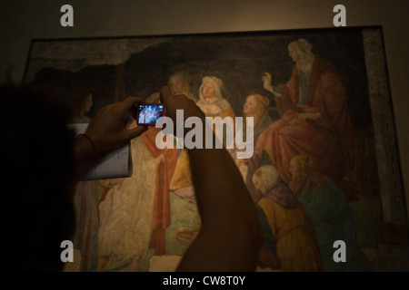 Tourist uses camera to record details of a medieval fresco by the Italian artist Alessandro di Mariano di Vanni Filipepi, better known as Sandro Botticelli. Stock Photo