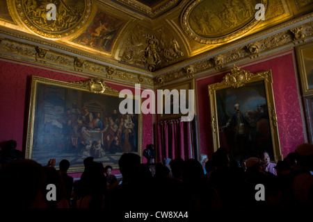 Tourists crowd in the Salon de Mars in the King’s Grand Apartment, Versaille, Paris. The choice of this military theme which inspired all the decoration of the salon can be explained by the fact that this large room was originally meant to serve as the guard room for the parade apartment. It was later reserved, at evening soirees, for music and dancing, so that it was commonly known as the 'ballroom'. The court ballets were strictly regulated and required many rehearsals; the princes took part in them, sometimes mixed in with professional dancers. Stock Photo
