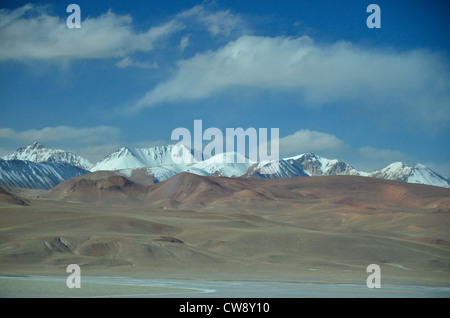 Touring the high altitude Altiplano of the Andes mountains in Bolivia, South America. Snowy mountaints, desert foreground, cloud