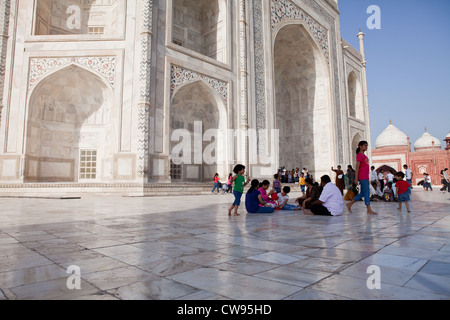 Indian families sitting and chatting on the white marble floor of the Taj Mahal Stock Photo