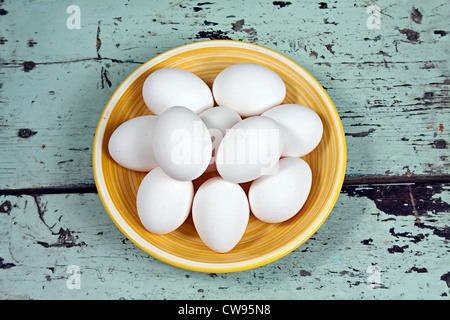 White eggs on a yellow plate, placed on a rustic wooden background Stock Photo