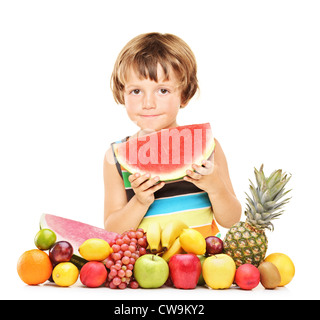 Boy eating a watermelon, standing behind fruits isolated on white background Stock Photo