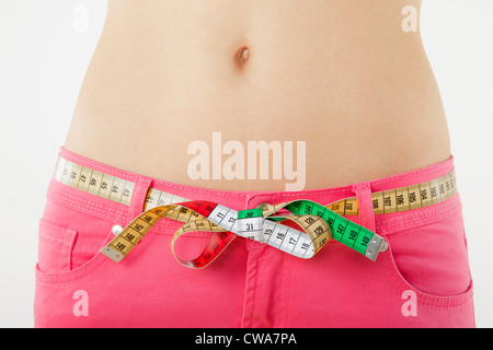 Young woman measuring waist with tape measure Stock Photo