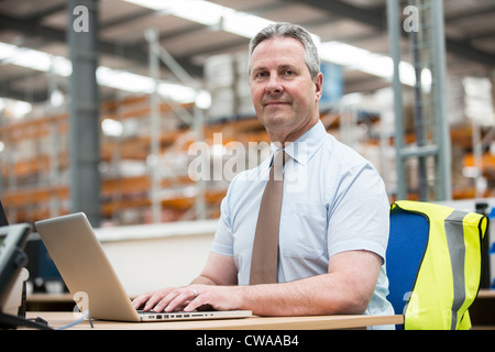 Man using laptop in warehouse, portrait Stock Photo