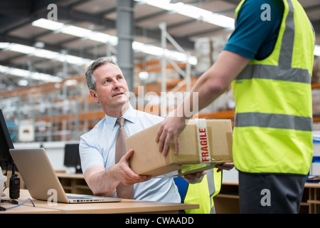 Man delivering cardboard box to another man Stock Photo