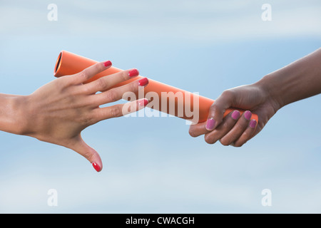 Hands of female relay athletes passing a baton, close up Stock Photo