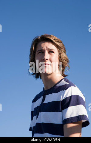 Teenage boy wearing blue and white striped t shirt against blue sky, portrait Stock Photo