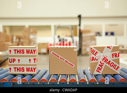 Three cardboard boxes with parcel tape on conveyor belt Stock Photo
