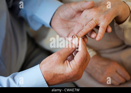 Senior man placing wedding ring on senior womans finger Stock Photo