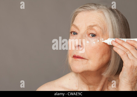 Senior woman applying eye cream Stock Photo