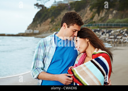 Young couple on beach, woman wrapped in towel Stock Photo