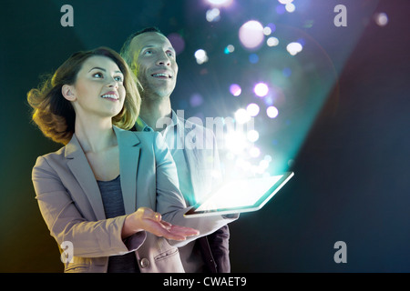 Businesspeople looking at lights coming from digital tablet Stock Photo