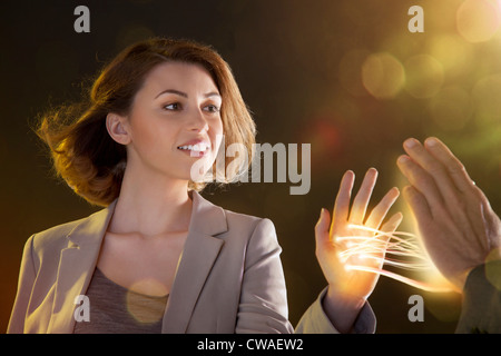 Young woman touching light streams, connecting to another person Stock Photo