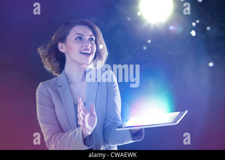 Young woman looking at lights coming from digital tablet Stock Photo