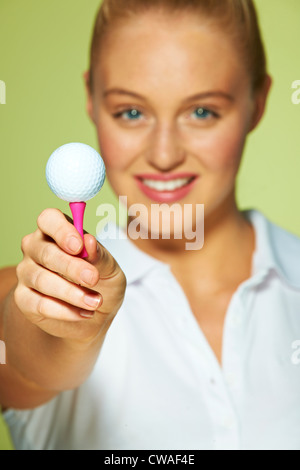 Young woman holding golf ball and tee Stock Photo