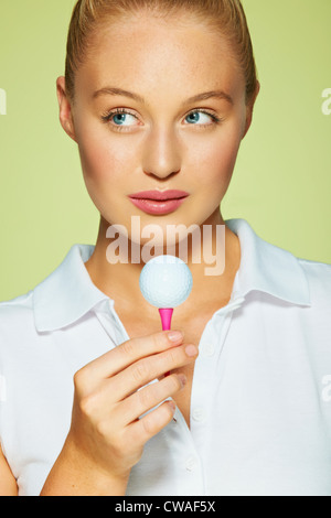 Young woman holding golf ball and tee Stock Photo