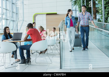 Young couple with suitcase on ramp to canteen area Stock Photo