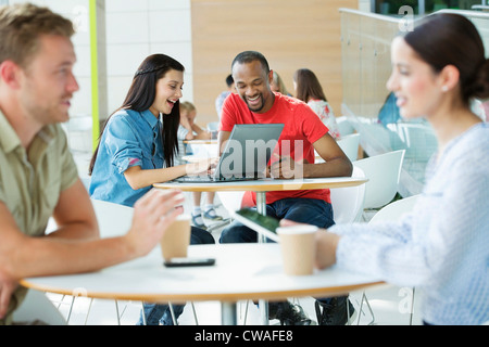 Young couple in canteen area, looking at laptop Stock Photo