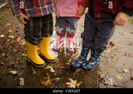 Three children wearing wellington boots Stock Photo
