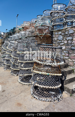 Lobster pots stacked against the harbour wall in Brixham Stock Photo