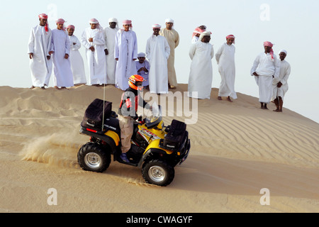 Dubai, a group of Arab men watched a quad riders in the desert Stock Photo