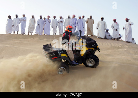 Dubai, a group of Arab men watched a quad riders in the desert Stock Photo