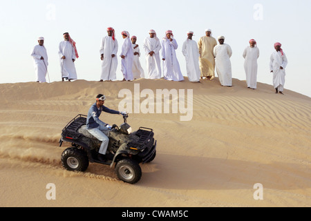 Dubai, a group of Arab men watched a quad riders in the desert Stock Photo