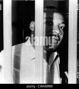 MARTIN LUTHER KING, JR, peers between the bars of his jail cell in the ...