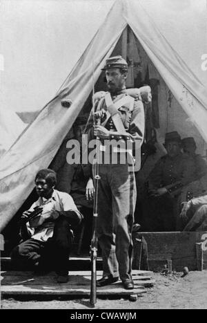 A New York State soldier poses before his tent at Camp Cameron holding his bayoneted rifle with an African American Stock Photo