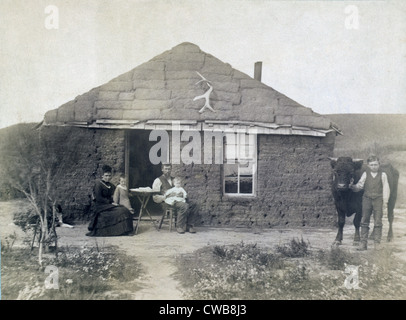 Rural life in Nebraska. The Laulerman family in front of their sod house, with boy holding bull on the right. 1886 Stock Photo