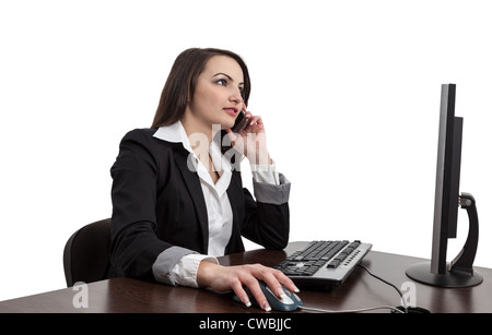 Image of a young brunette woman working on a computer and using a mobile phone , isolated against a white background. Stock Photo