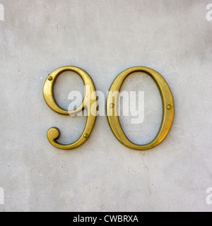 brass house number ninety on a white wall Stock Photo