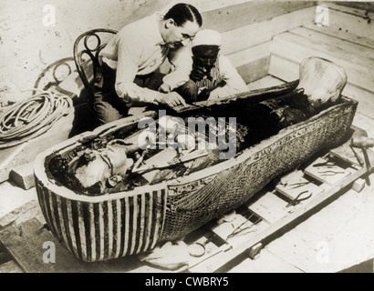 Howard Carter (1873-1939), seated beside coffin of King Tutankhamen, removing the consecration oils which covered the third or Stock Photo
