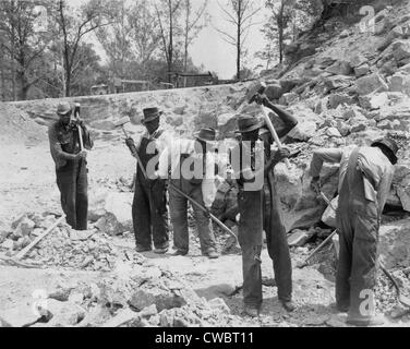 African American convicts in a Southern work gang breaking up rocks with sledge hammers. Ca. 1940. Stock Photo