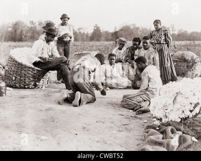 African Americans enjoying some rest and recreation after a day of work picking cotton. Three men are shooting dice on the edge Stock Photo