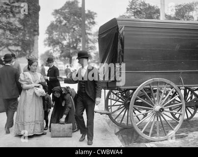 Two women immigrants and a child engage a wagon for transport to their next stop, probably a boarding house or railroad Stock Photo