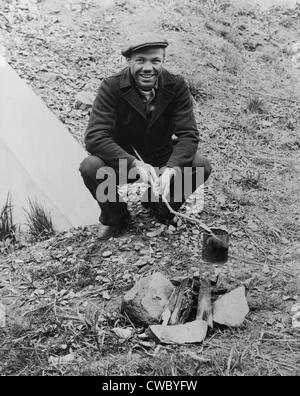 Hobo, Lou Ambers, cooking over a campfire with a tin can on a stick, during the Great Depression. 1935. Stock Photo