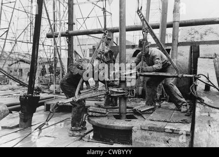 Oil rig workers, called roughnecks, at work, loosening sections of pipe on an drilling platform, Kilgore, Texas. 1939 Photo by Stock Photo