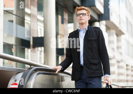 Businessman standing on escalator Stock Photo