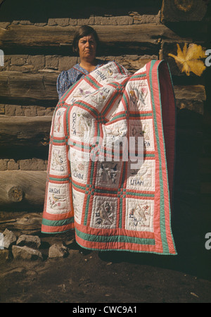 Mrs. Bill Stagg displays her 'state quilt' in front of her log home in Pie Town New Mexico. The quilt had embroidered panes of Stock Photo