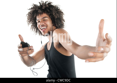 Portrait of a happy young man in vest dancing to tunes of mp3 player over white background Stock Photo