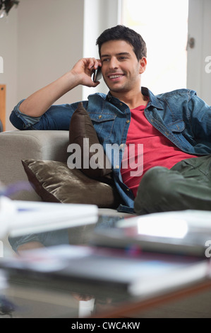 Man reclining on a couch and talking on a mobile phone Stock Photo