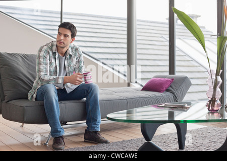 Man sitting on a couch and drinking coffee Stock Photo