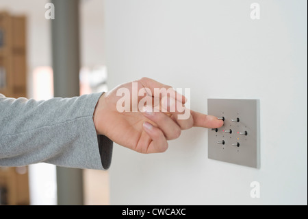 Close-up of a man's hand pressing light switch on a wall Stock Photo